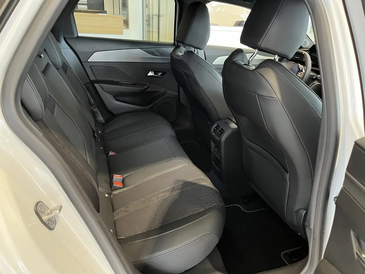 Vue intérieure côté gauche des sièges arrière noirs en cuir et tissu de la Peugeot 308 SW blanc okenite 2025.