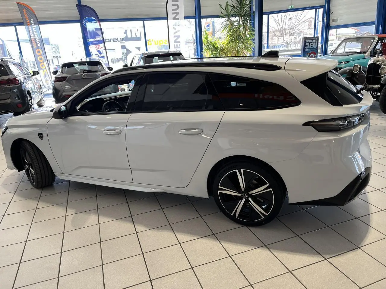 Peugeot 308 SW BlueHDi 130ch GT blanc okenite vue de profil côté gauche en intérieur showroom.