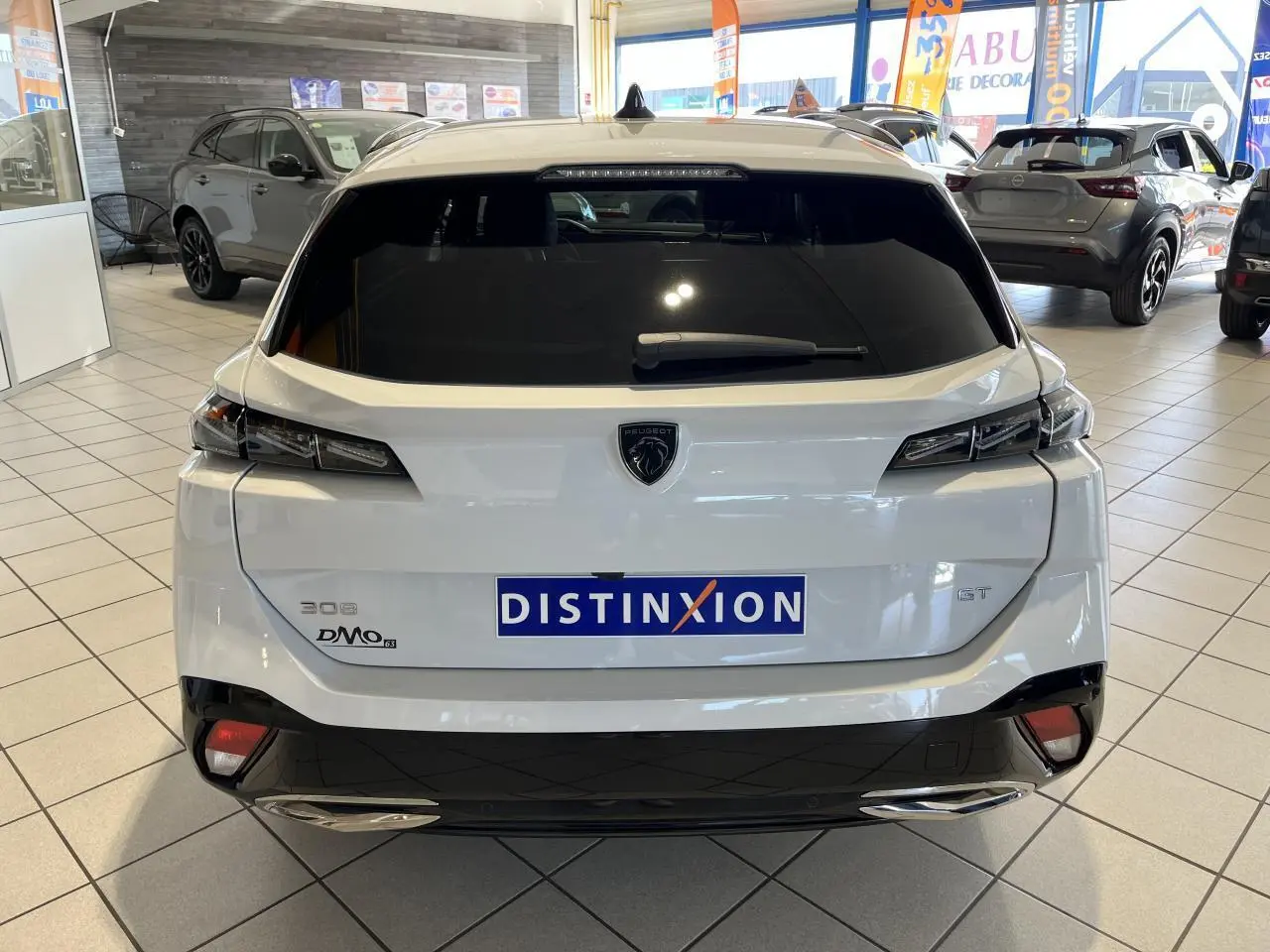 Vue arrière d'une Peugeot 308 SW GT blanche Okenite avec feux arrière LED et double sortie d'échappement chromée en concession.