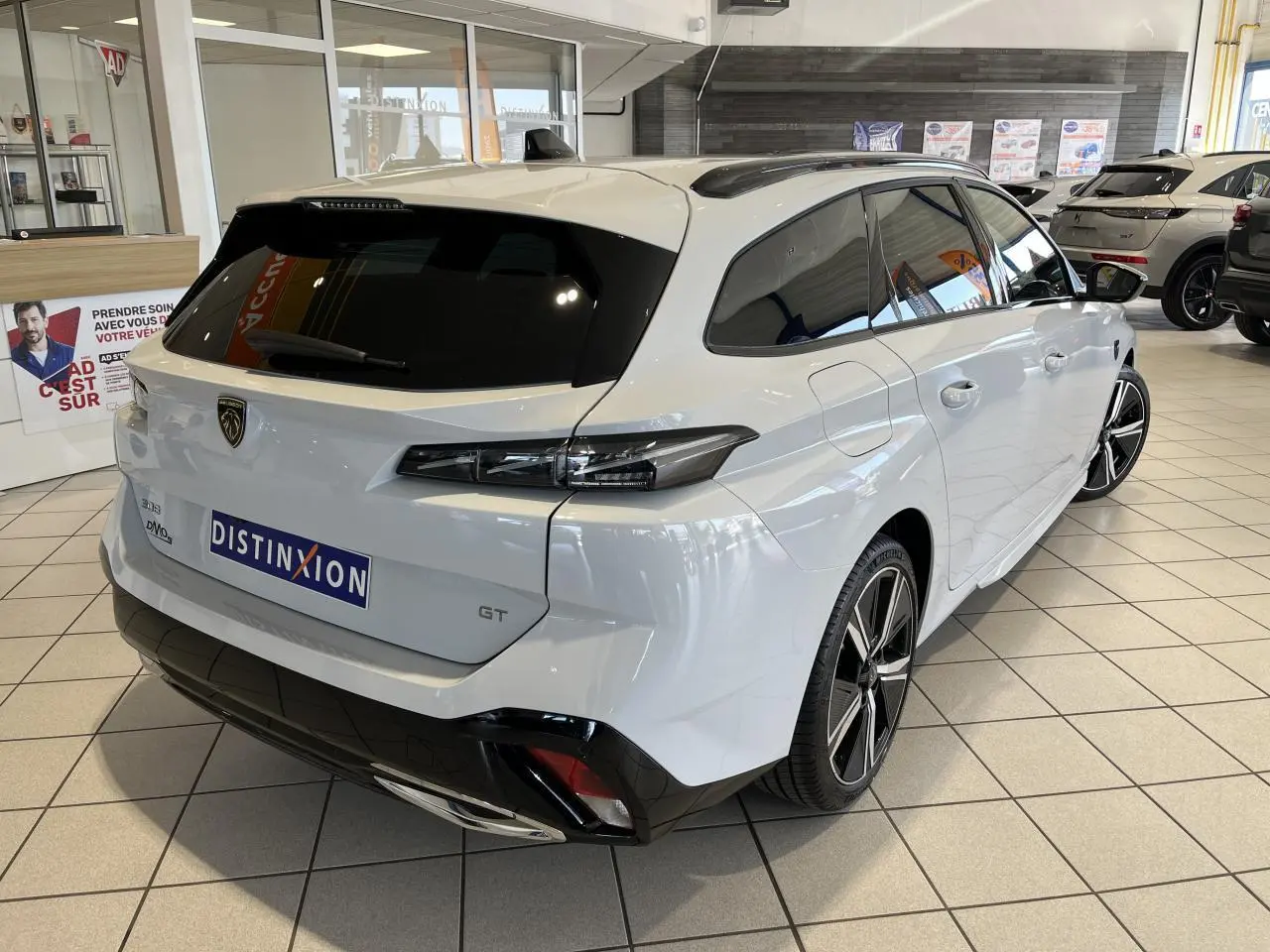 Peugeot 308 SW GT blanc okenite vue 3/4 arrière droit en intérieur avec jantes alliage et vitres surteintées.