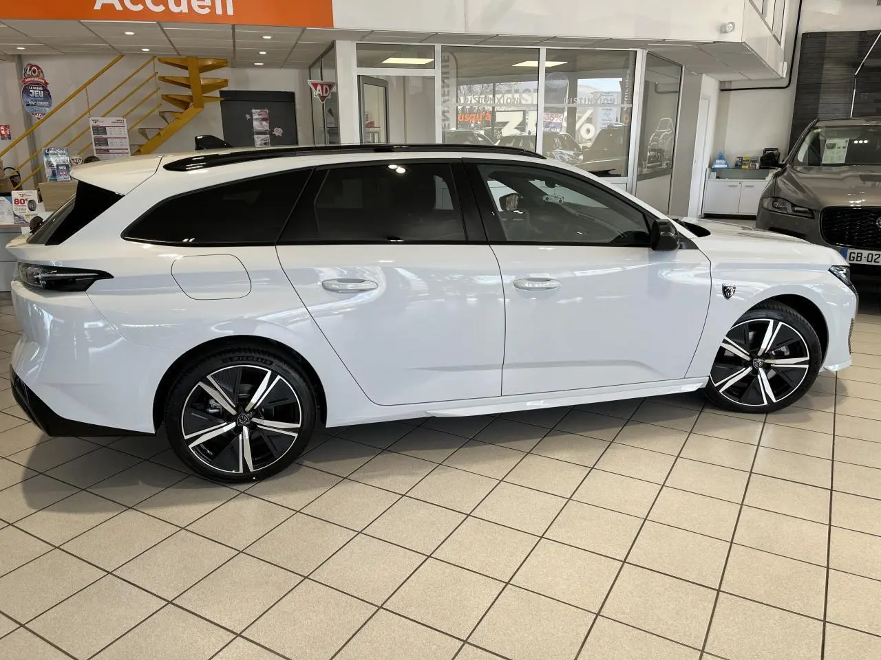 Peugeot 308 SW BlueHDi 130ch GT blanc okenite vue de profil côté droit en intérieur showroom.