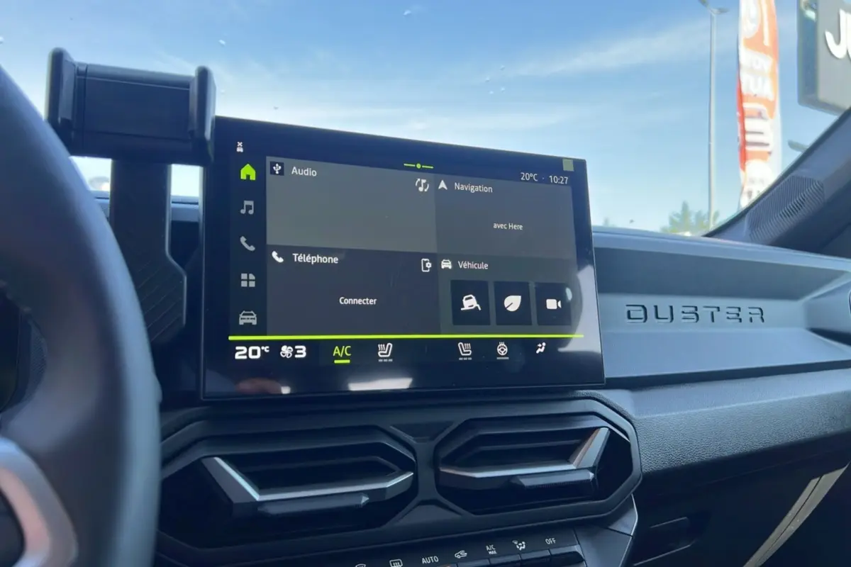 Intérieur du Dacia Duster 2025 blanc glacier, vue du tableau de bord avec écran tactile et aérateurs hexagonaux.