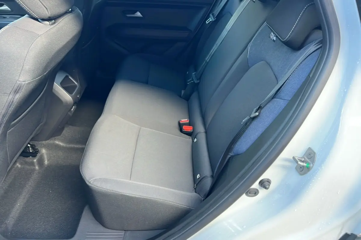 Vue intérieure sur la banquette arrière du Dacia Duster blanc glacier 2025, montrant les sièges en tissu gris et bleu.