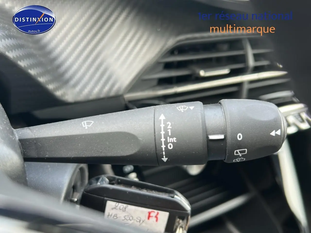 Gros plan sur la commande d’essuie-glace côté gauche du tableau de bord d’une Peugeot 208 gris artense 2025.