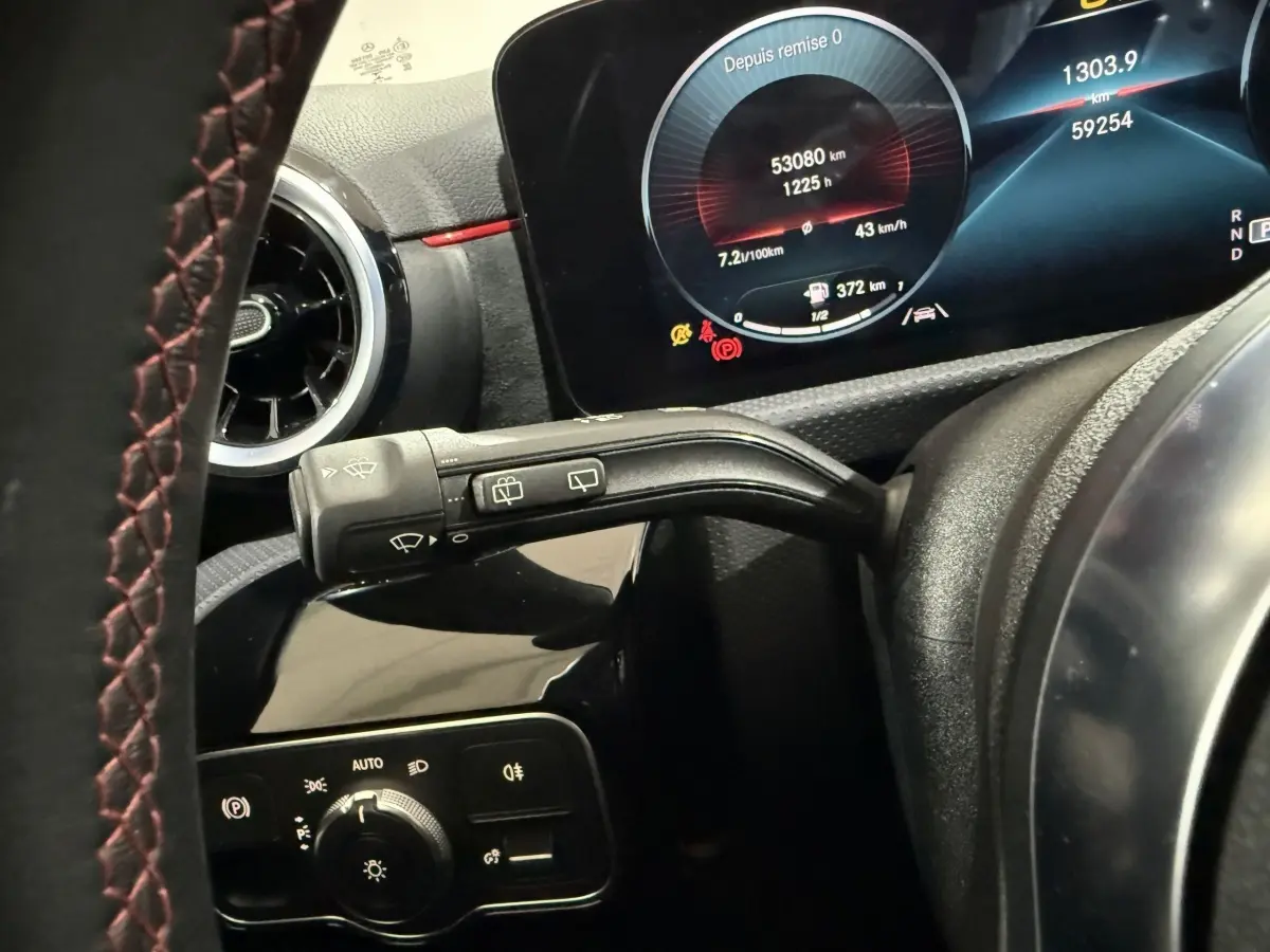 Gros plan sur le tableau de bord et levier d’essuie-glace d’une Mercedes Classe A A 200 AMG Line 2021, intérieur noir avec surpiqûres rouges.
