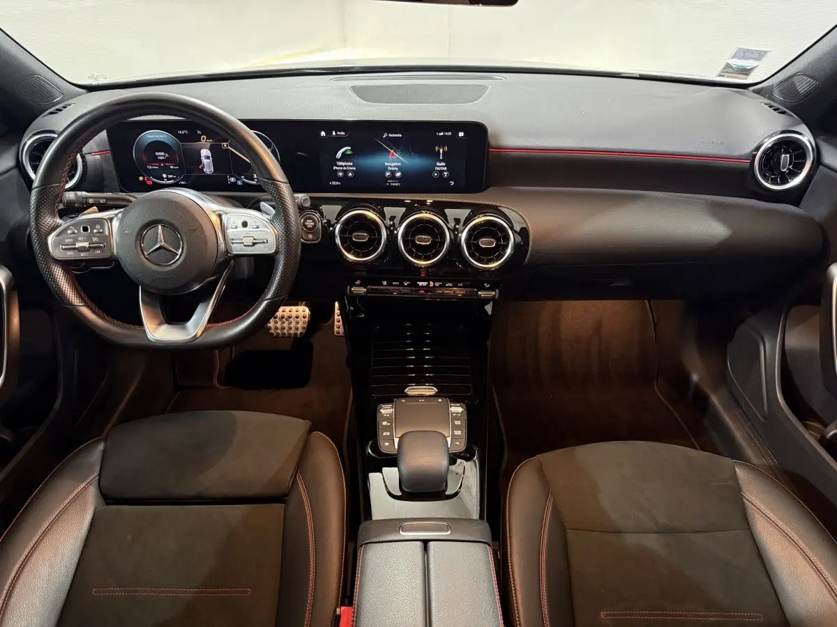 Vue intérieure frontale du tableau de bord et volant cuir noir avec surpiqûres rouges de la Mercedes Classe A A 200 AMG Line.