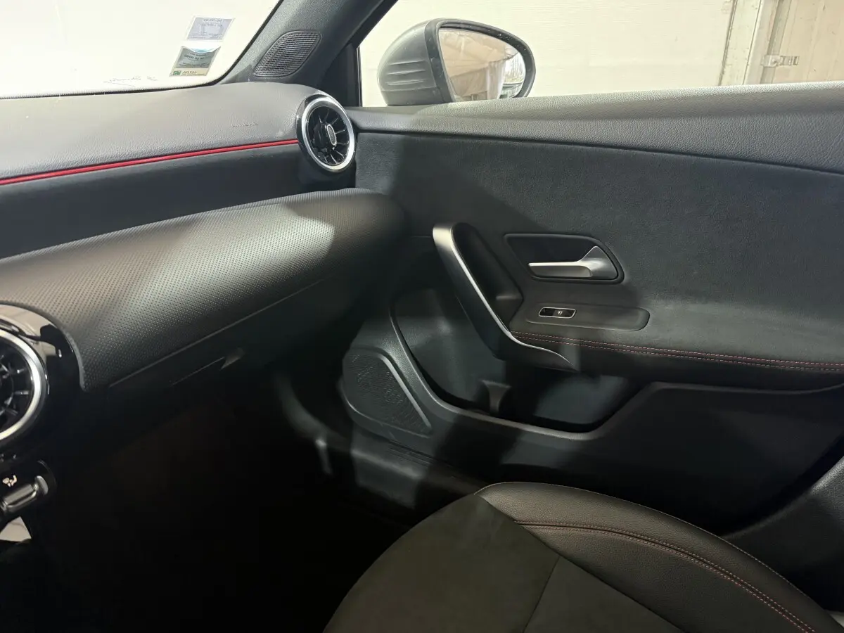 Vue intérieure côté passager de la Mercedes Classe A 200 AMG Line 2021, avec garnitures noires et surpiqûres rouges.