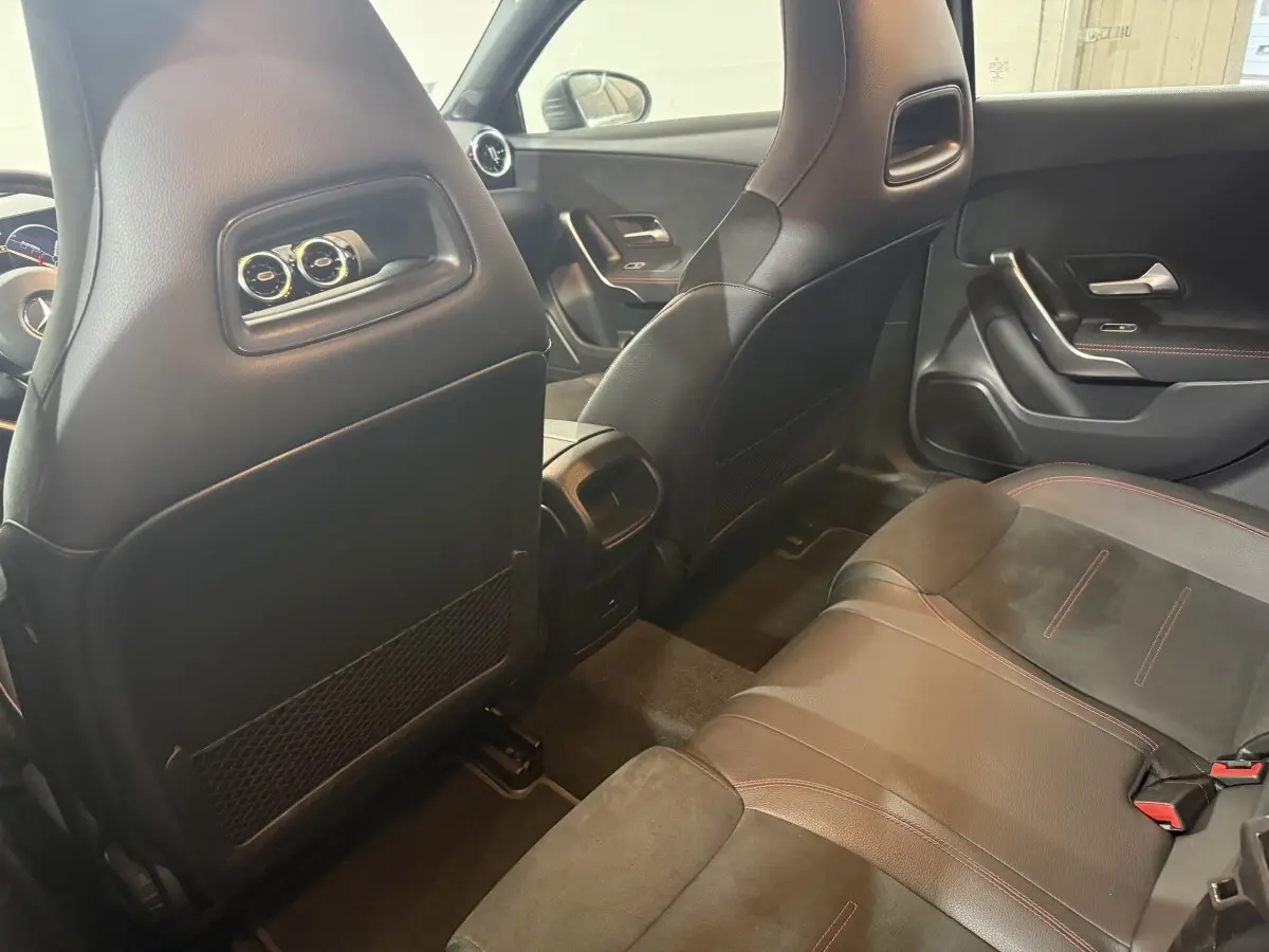 Vue intérieure arrière montrant les sièges noirs avec surpiqûres rouges et le dossier des sièges avant d'une Mercedes Classe A AMG Line 2021.