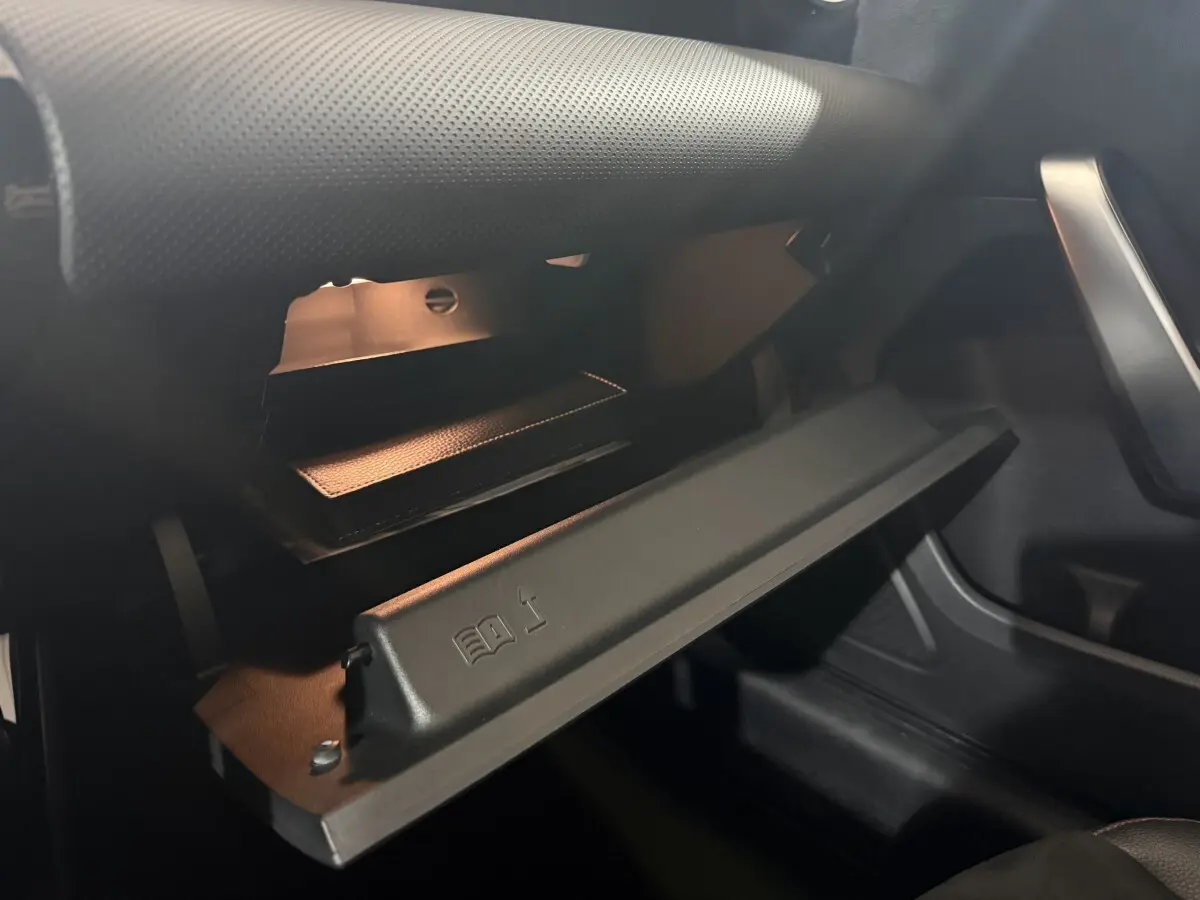 Gros plan de la boîte à gants ouverte du Mercedes Classe A 200 AMG Line 2021, intérieur noir avec éclairage doux.