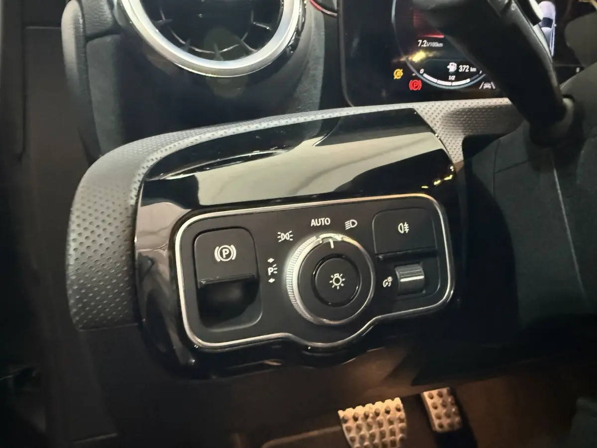 Gros plan sur le panneau de commande des phares et du frein à main électrique dans une Mercedes Classe A A 200 AMG Line 2021.