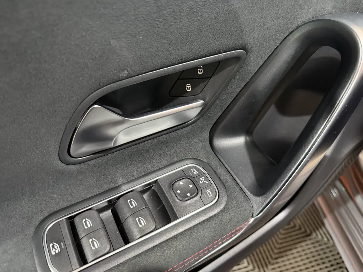 Gros plan sur la porte côté conducteur de la Mercedes Classe A 200 AMG Line 2021, garniture noire avec surpiqûres rouges.