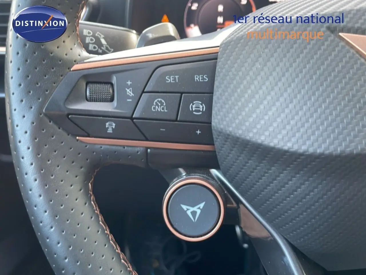 Gros plan sur le volant perforé et multifonction de la CUPRA Formentor blanc neige, avec logo distinctif au centre.