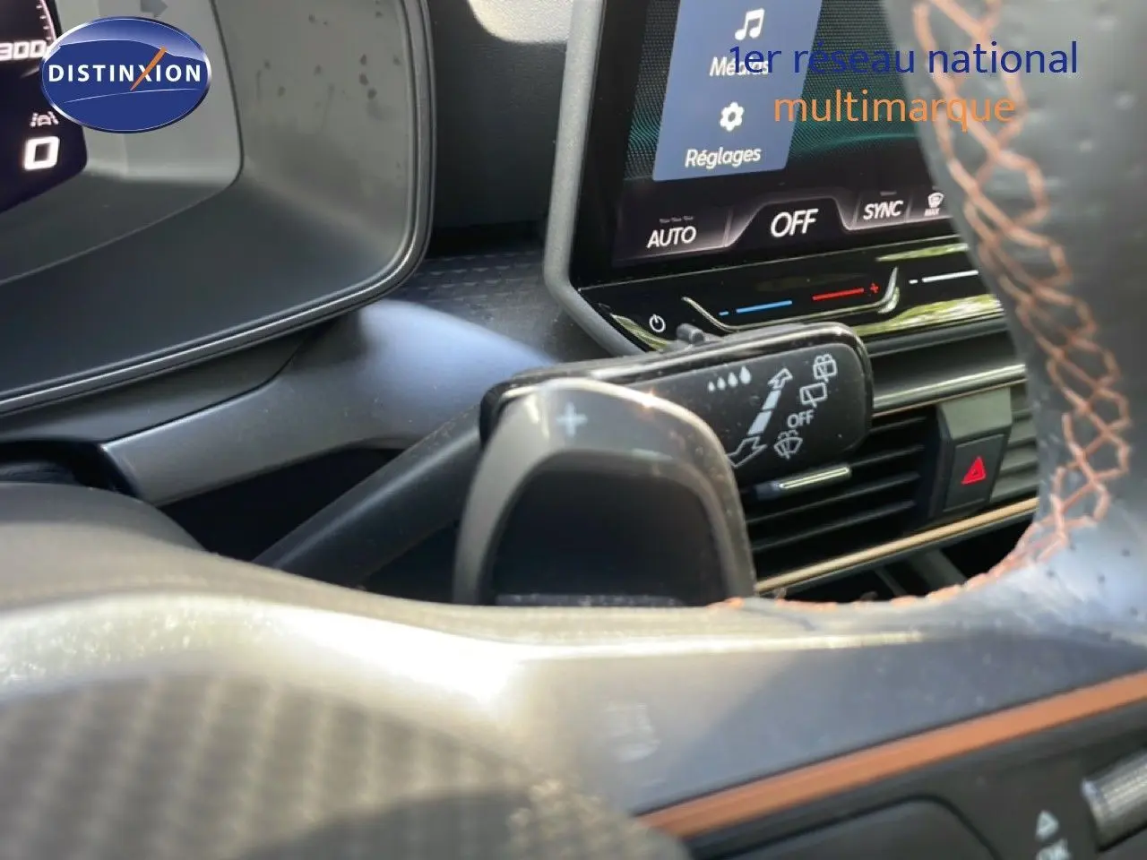 Gros plan intérieur sur le volant et la commande de clignotant du CUPRA Formentor blanc neige, avec affichage digital et détails orange.