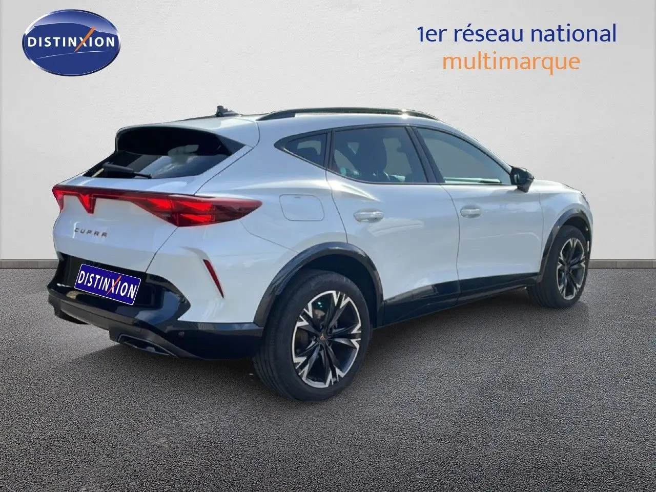 Vue 3/4 arrière droite d'un CUPRA Formentor blanc neige métal avec jantes noires et détails noirs contrastants.