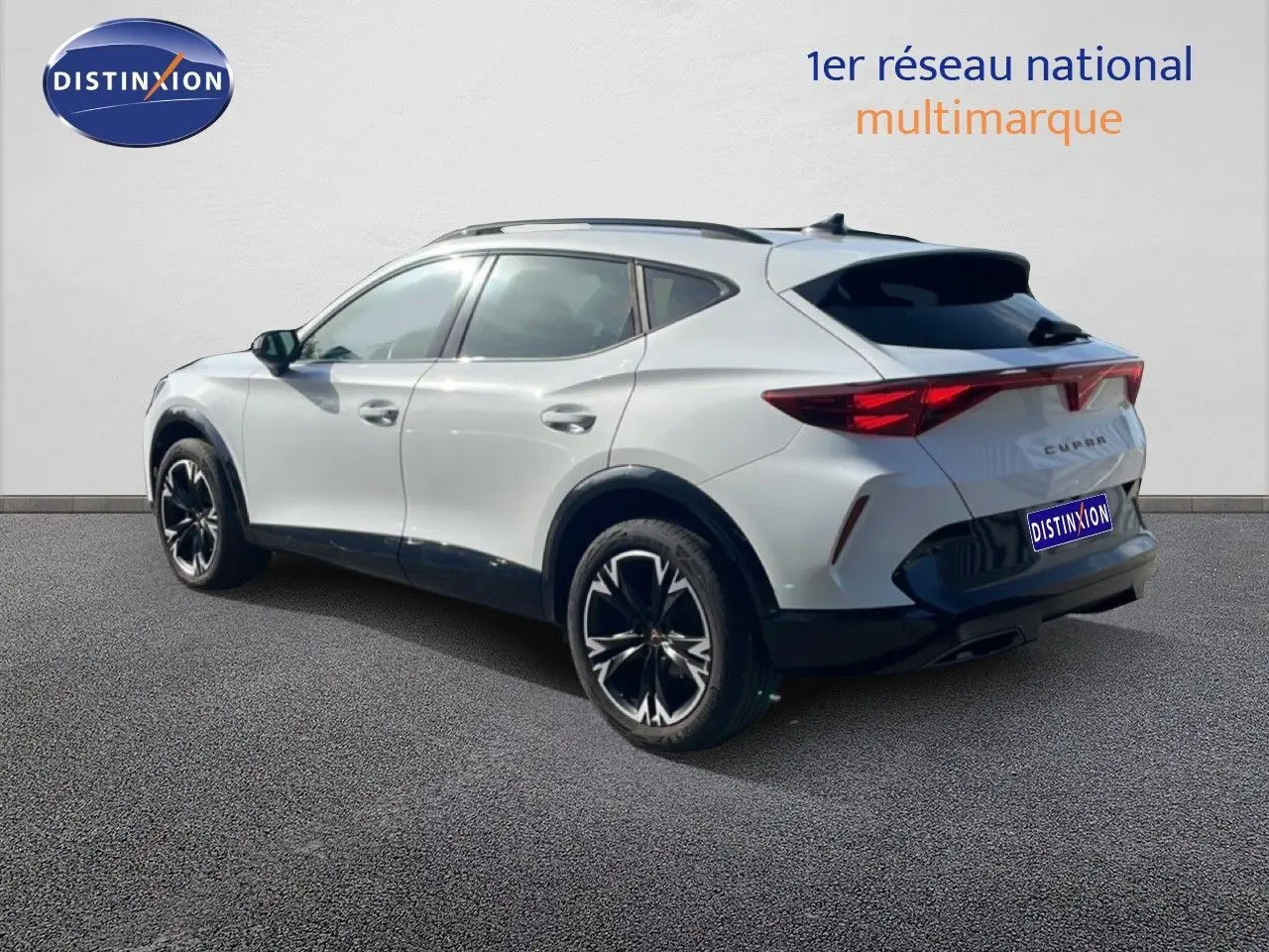 Vue 3/4 arrière droite d'un CUPRA Formentor blanc neige métal avec jantes noires et détails noirs contrastants.