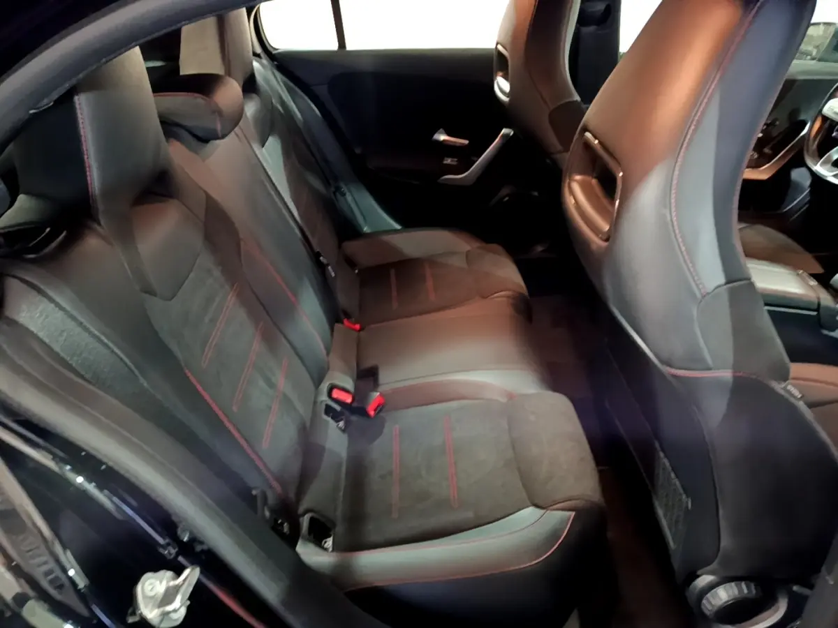 Vue intérieure arrière côté gauche de la Mercedes Classe A 200 AMG Line 2021, sièges noirs avec surpiqûres rouges.