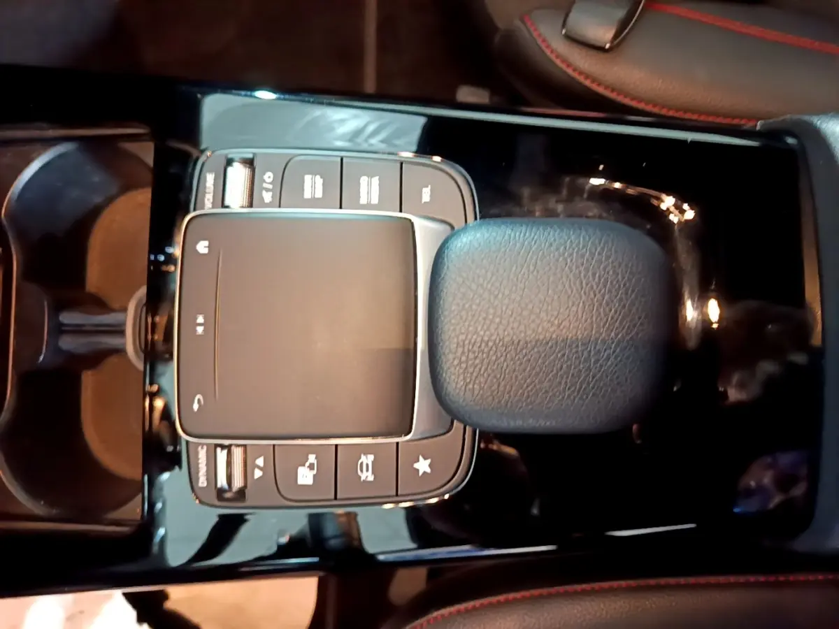 Gros plan sur la console centrale noire de la Mercedes Classe A 200 AMG Line, avec pavé tactile et accoudoir cuir.