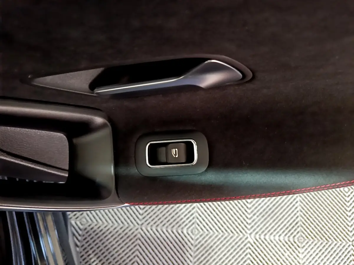 Détail intérieur de la porte côté conducteur de Mercedes Classe A 200 AMG Line noire, avec bouton ouverture coffre et surpiqûres rouges.