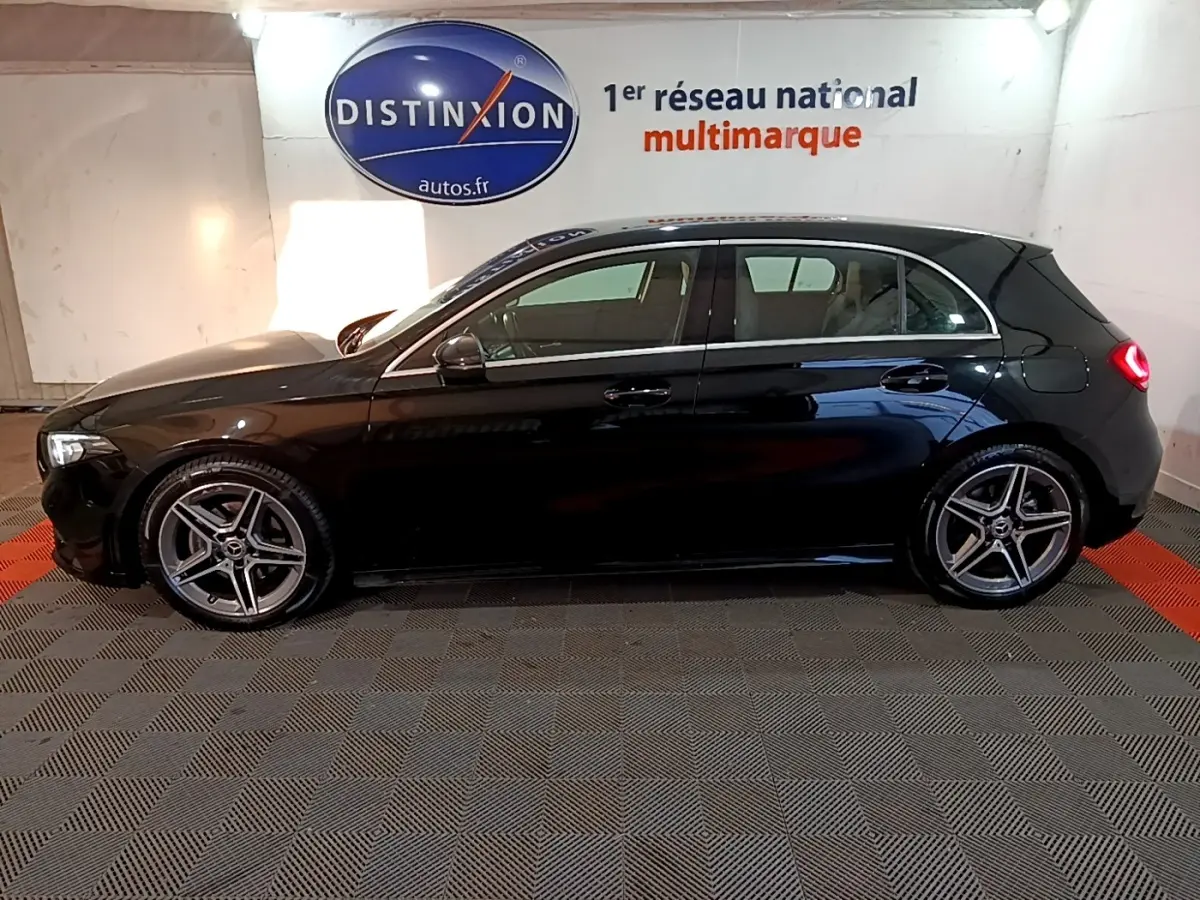 Vue de profil côté gauche d'une Mercedes Classe A 200 AMG Line noire, avec jantes alliage et feux arrière allumés.