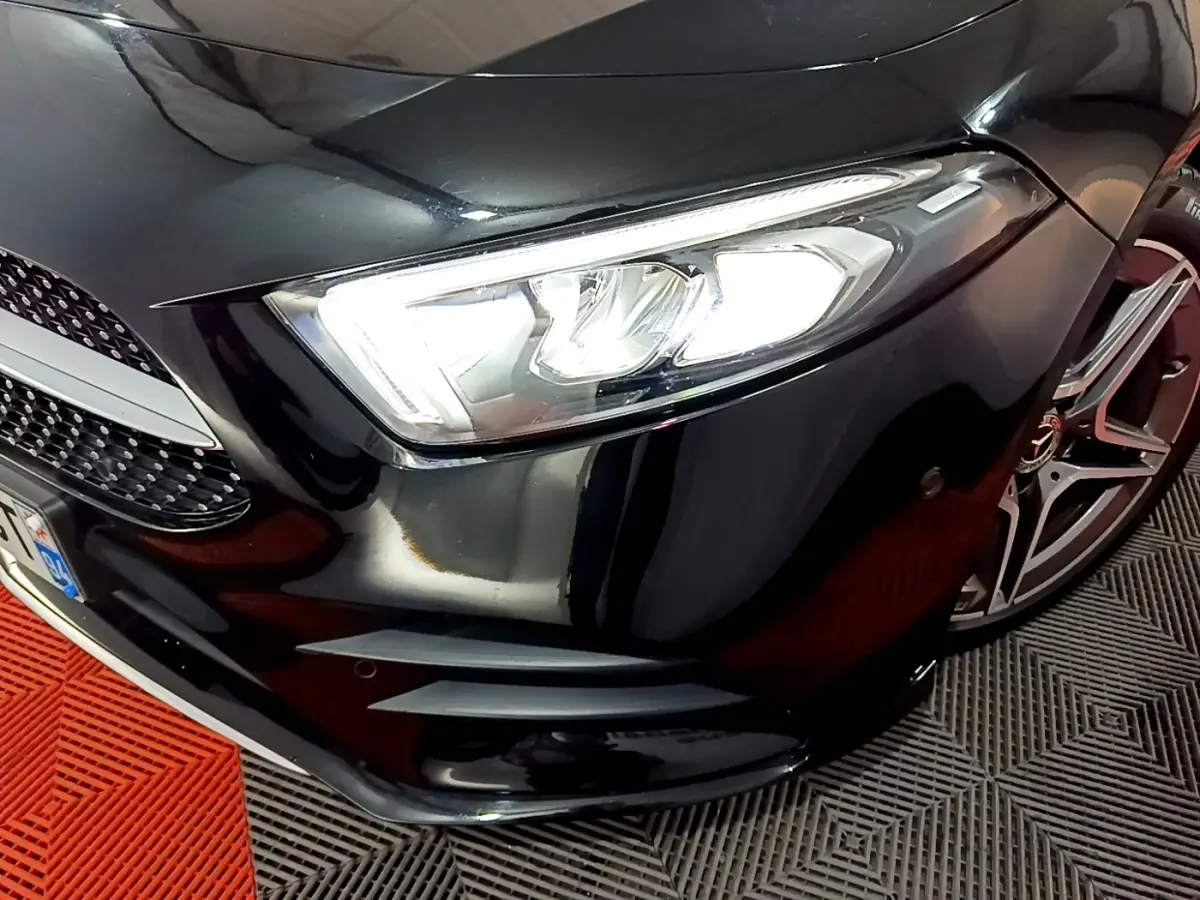 Gros plan sur le phare avant droit et la calandre noire brillante d'une Mercedes Classe A 200 AMG Line 2021.