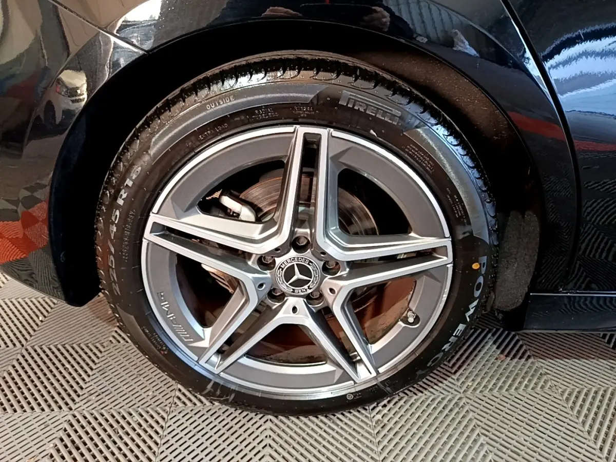 Gros plan sur la roue avant droite noire d'une Mercedes Classe A 200 AMG Line avec jante étoile AMG grise.