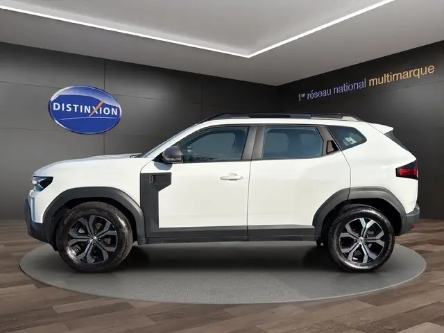 Vue latérale droite d'un Dacia Duster Expression Hybrid 140 blanc avec jantes alliage et protections noires contrastantes.