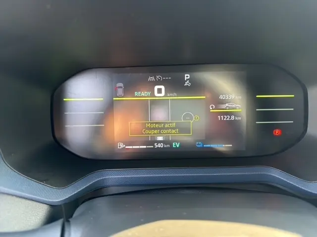 Combiné d'instruments numérique du Dacia Duster blanc 2025, affichage multifonctions avec alertes et autonomie EV visible.