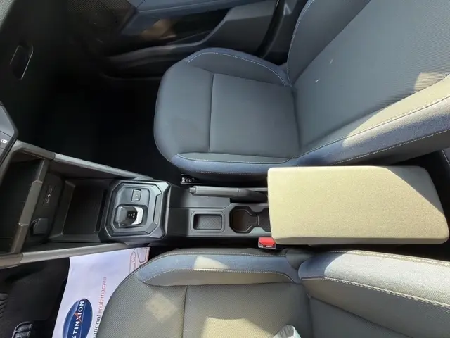 Vue plongeante sur l'intérieur du Dacia Duster blanc, montrant les sièges avant gris et la console centrale avec boîte automatique.