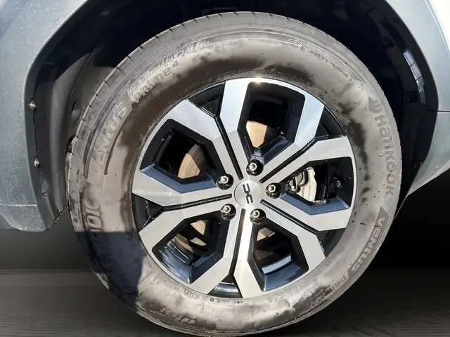 Gros plan sur la roue avant droite du Dacia Duster blanc 2025, mettant en valeur la jante alliage au design moderne.