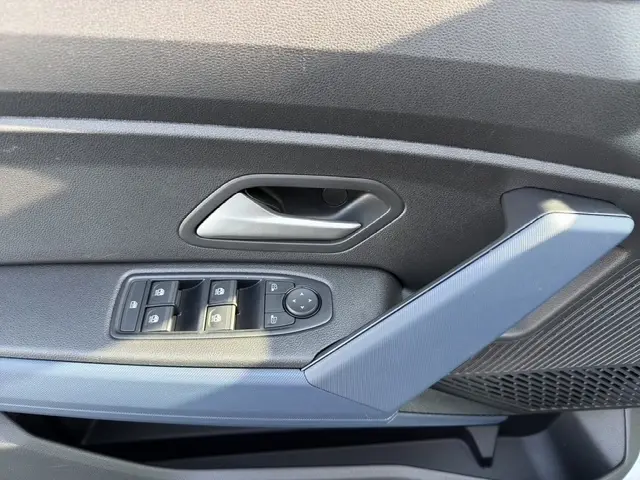 Gros plan sur la porte intérieure côté conducteur du Dacia Duster blanc, avec commandes des vitres et poignée grise.