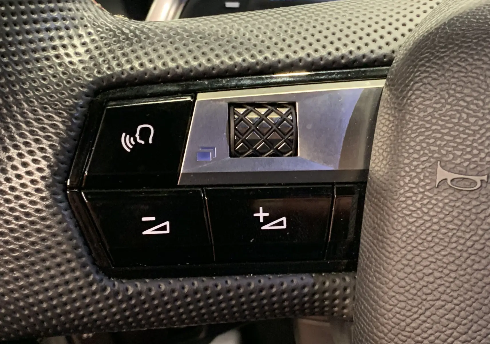 Gros plan sur les commandes de volume et de reconnaissance vocale sur le volant perforé noir du DS7 Crossback Gris Platinium 2022.
