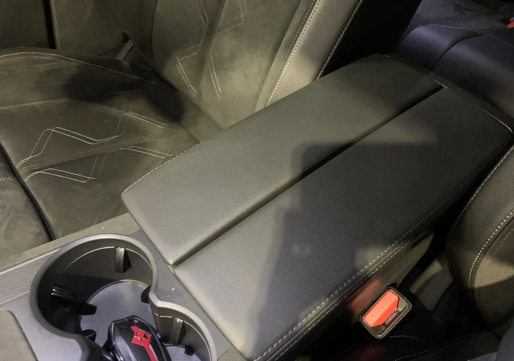 Gros plan sur l'accoudoir central noir et les sièges en cuir et alcantara avec surpiqûres blanches du DS7 Crossback 2022.