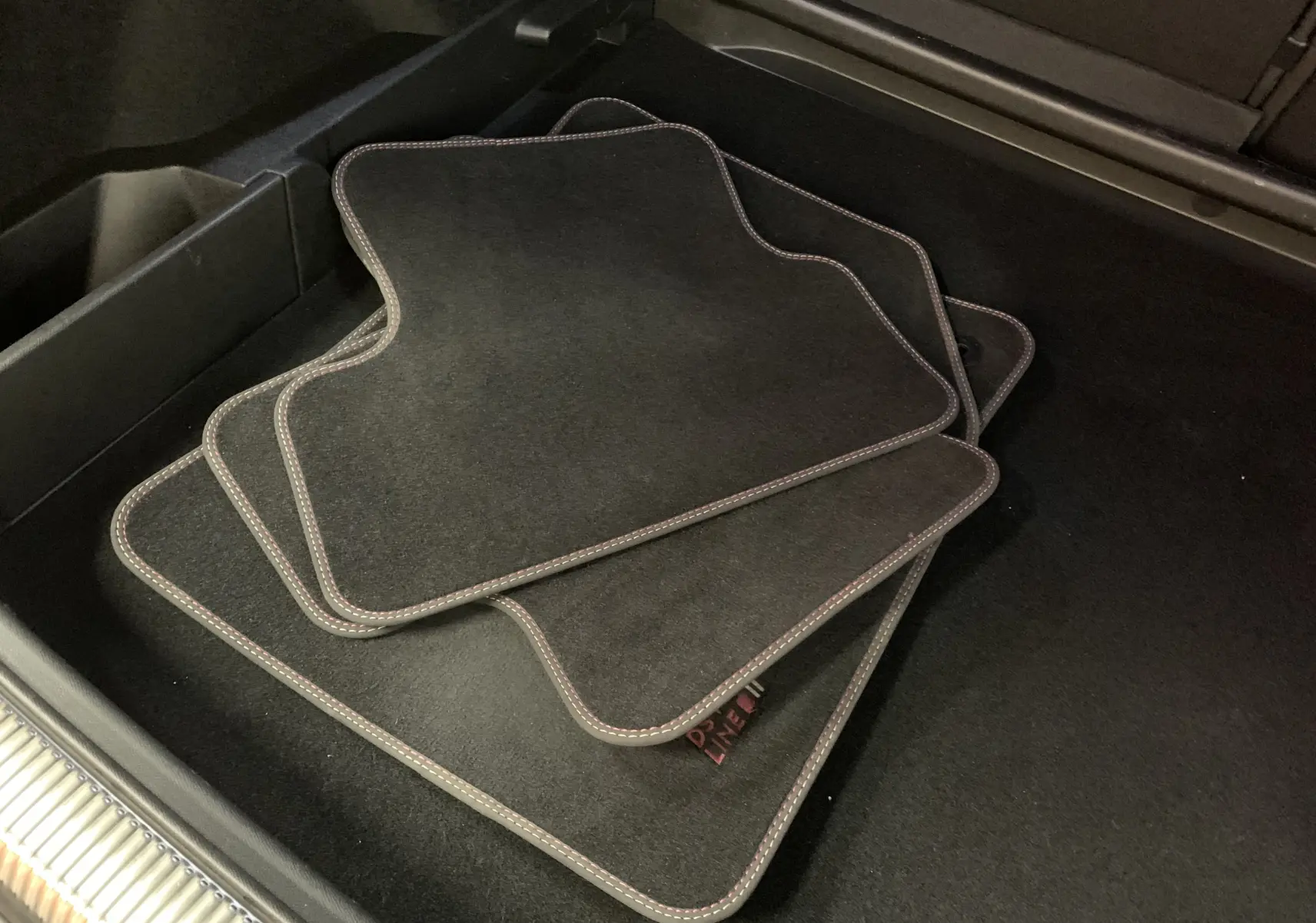 Gros plan sur les tapis de sol noirs avec surpiqûres claires dans le coffre du DS7 Crossback Gris Platinium 2022.