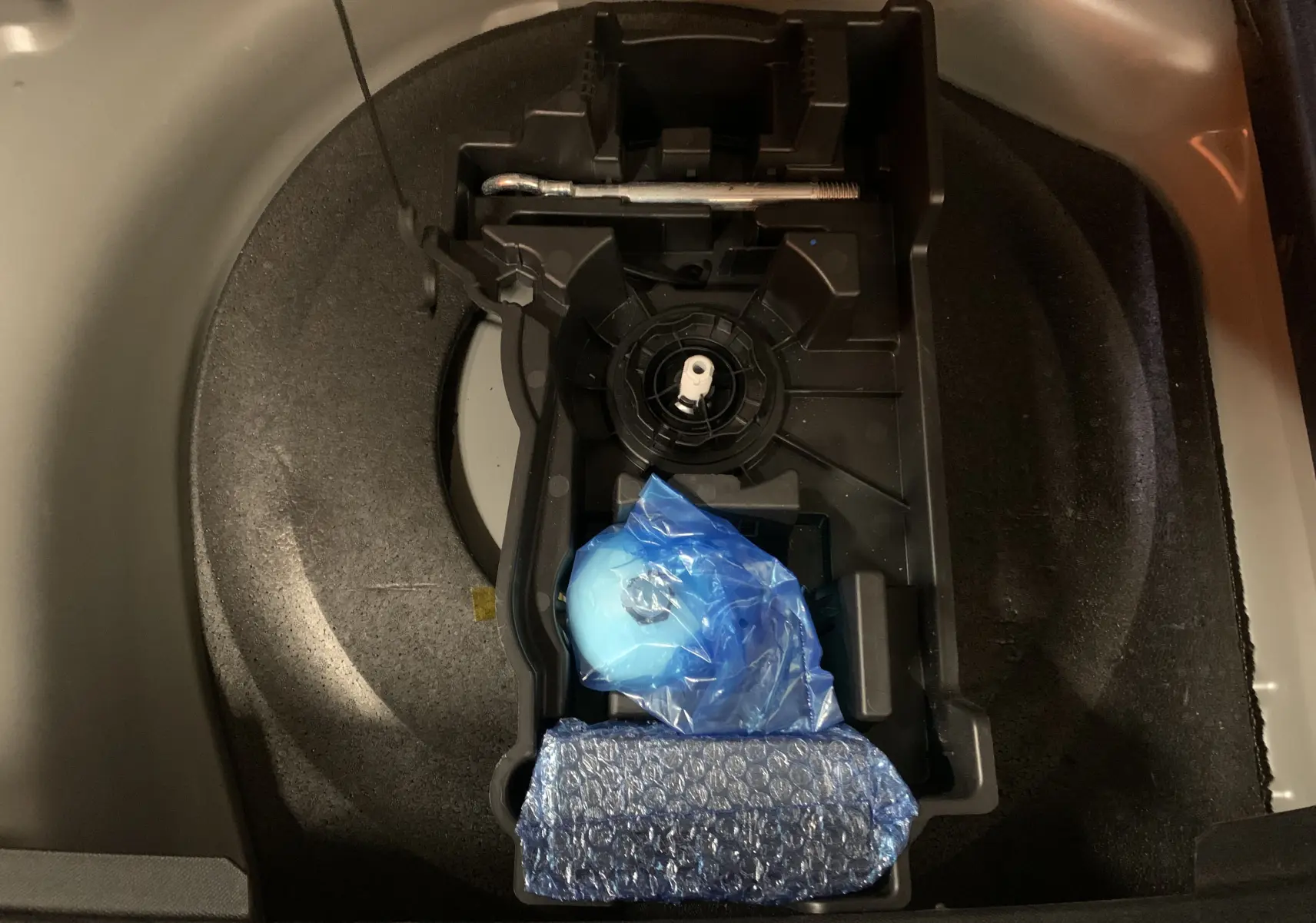 Vue plongeante sur le compartiment de rangement sous le coffre du DS7 Crossback gris Platinium, avec outils emballés visibles.