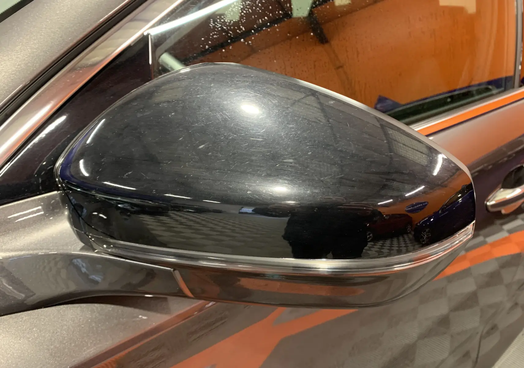 Rétroviseur extérieur droit noir brillant du DS7 Crossback gris Platinium, vue rapprochée sur la carrosserie et la vitre.