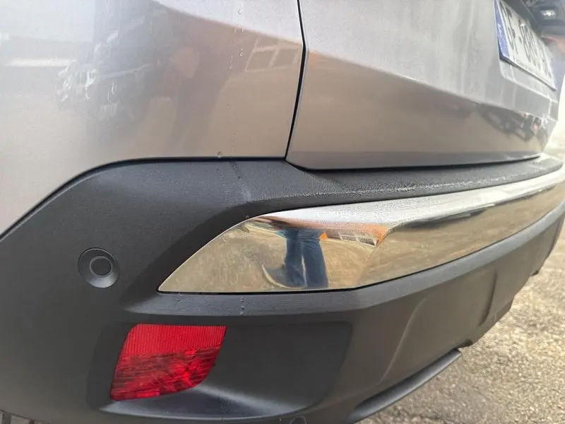 Gros plan sur le pare-chocs arrière droit gris Artense du Peugeot 3008 avec feu rouge et capteur de recul visible.