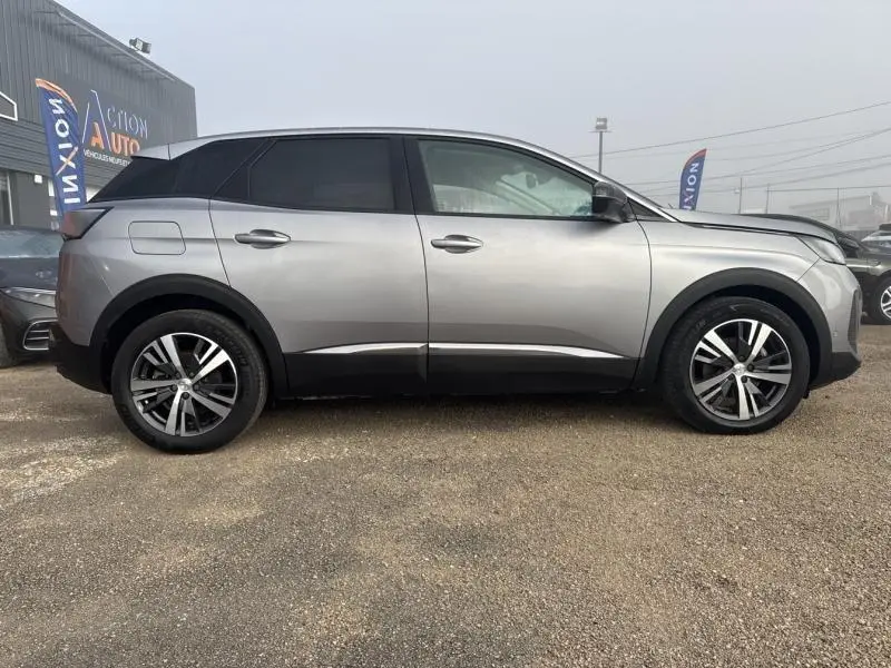 Profil côté gauche du Peugeot 3008 gris Artense avec jantes alliage et vitres surteintées sur fond de concession.