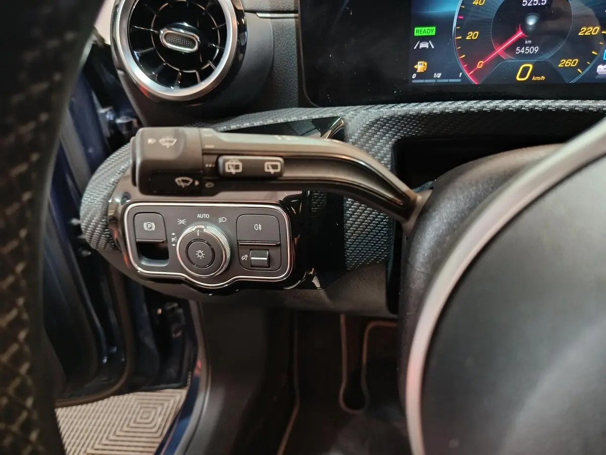 Vue rapprochée du tableau de bord côté gauche d’une Mercedes Classe A bleu, avec commandes d’éclairage et volant partiel.