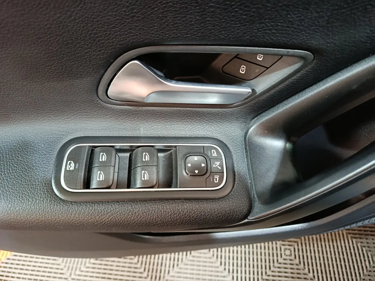 Détail de la porte côté gauche d’une Mercedes Classe A bleu, montrant les commandes des vitres et rétroviseurs.