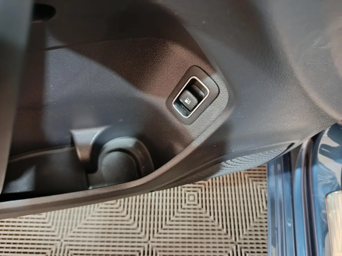 Détail intérieur du panneau de porte côté gauche avec bouton ouverture coffre, sur Mercedes Classe A bleu 2021.