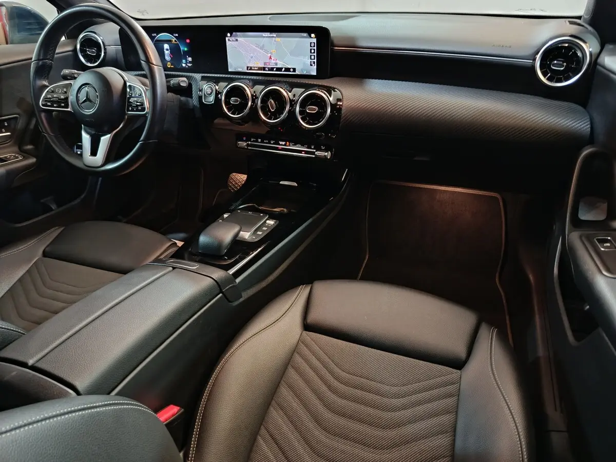 Vue intérieure avant droite de la Mercedes Classe A 250 e Business Line 2021, avec volant cuir et écran tactile large.