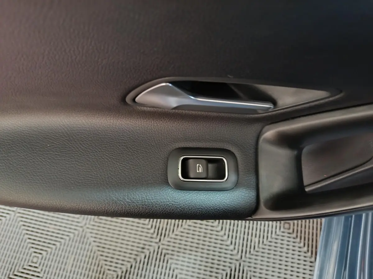 Gros plan sur la poignée intérieure et le bouton de verrouillage de la porte côté gauche d'une Mercedes Classe A bleu.