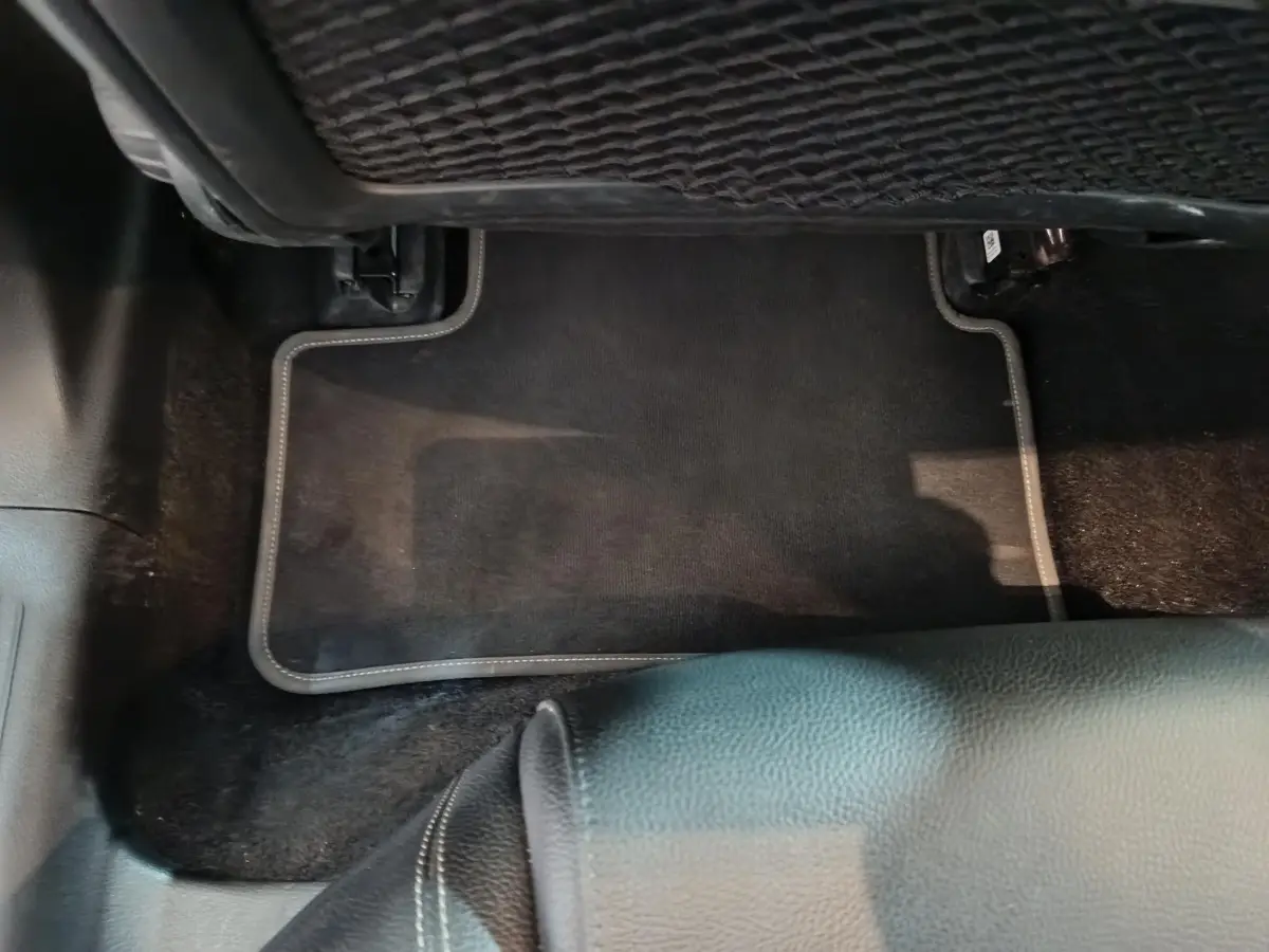 Vue rapprochée du tapis de sol noir et de la partie inférieure du siège en cuir dans une Mercedes Classe A bleu.