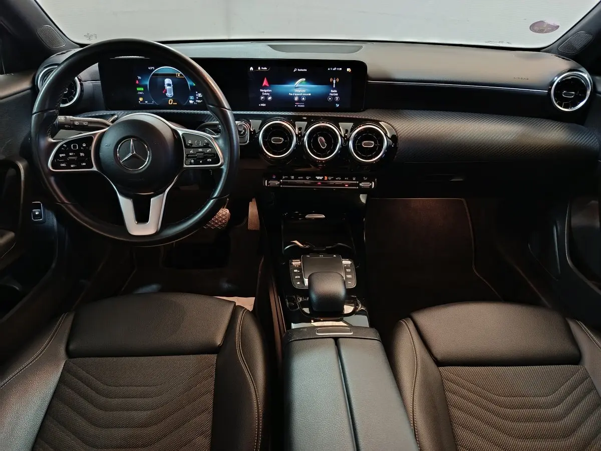 Vue intérieure avant de la Mercedes Classe A 250 e Business Line 2021 avec tableau de bord numérique et volant cuir multifonctions.