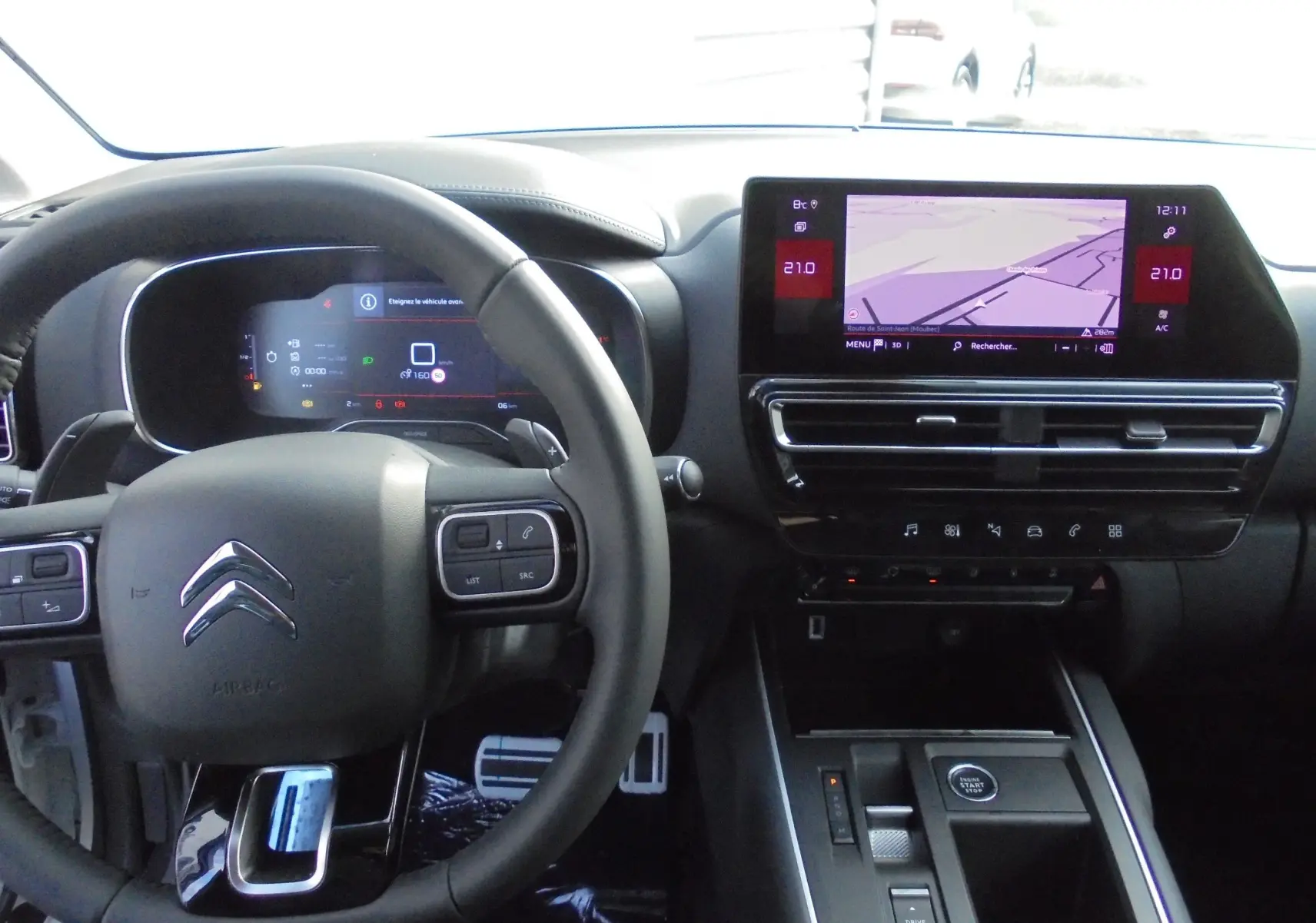 Intérieur du Citroën C5 Aircross blanc, vue du poste de conduite avec volant, tableau de bord numérique et écran central tactile.
