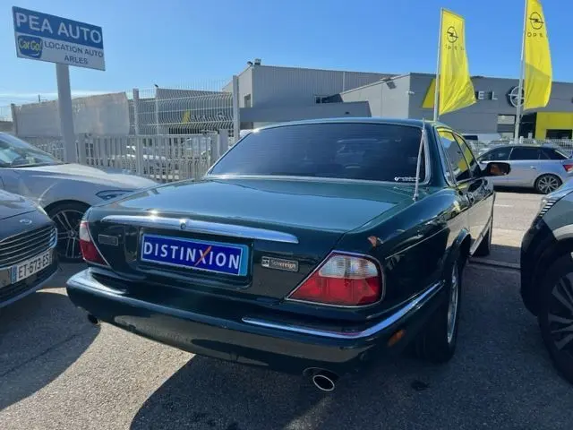 Vue 3/4 arrière droite d'une Jaguar Sovereign 3.2 V8 verte de 2002 avec finition chromée et plaque Distinxion.