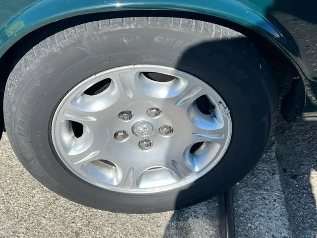 Gros plan sur la roue avant gauche d'une Jaguar Sovereign 3.2 V8 verte de 2002 avec jante argentée.