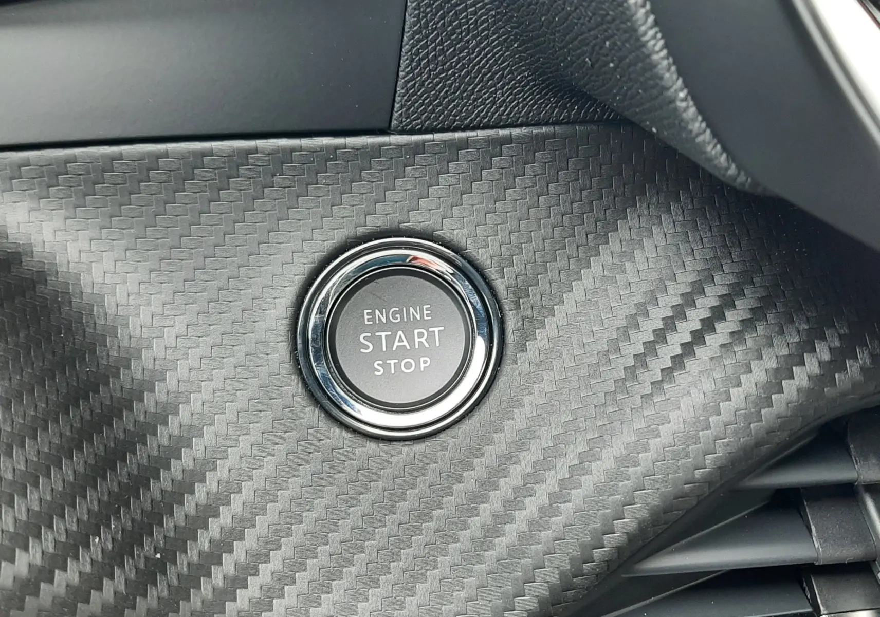 Bouton démarrage moteur sur tableau de bord en carbone du Peugeot 2008 1.2 Hybrid 145 finition Allure.