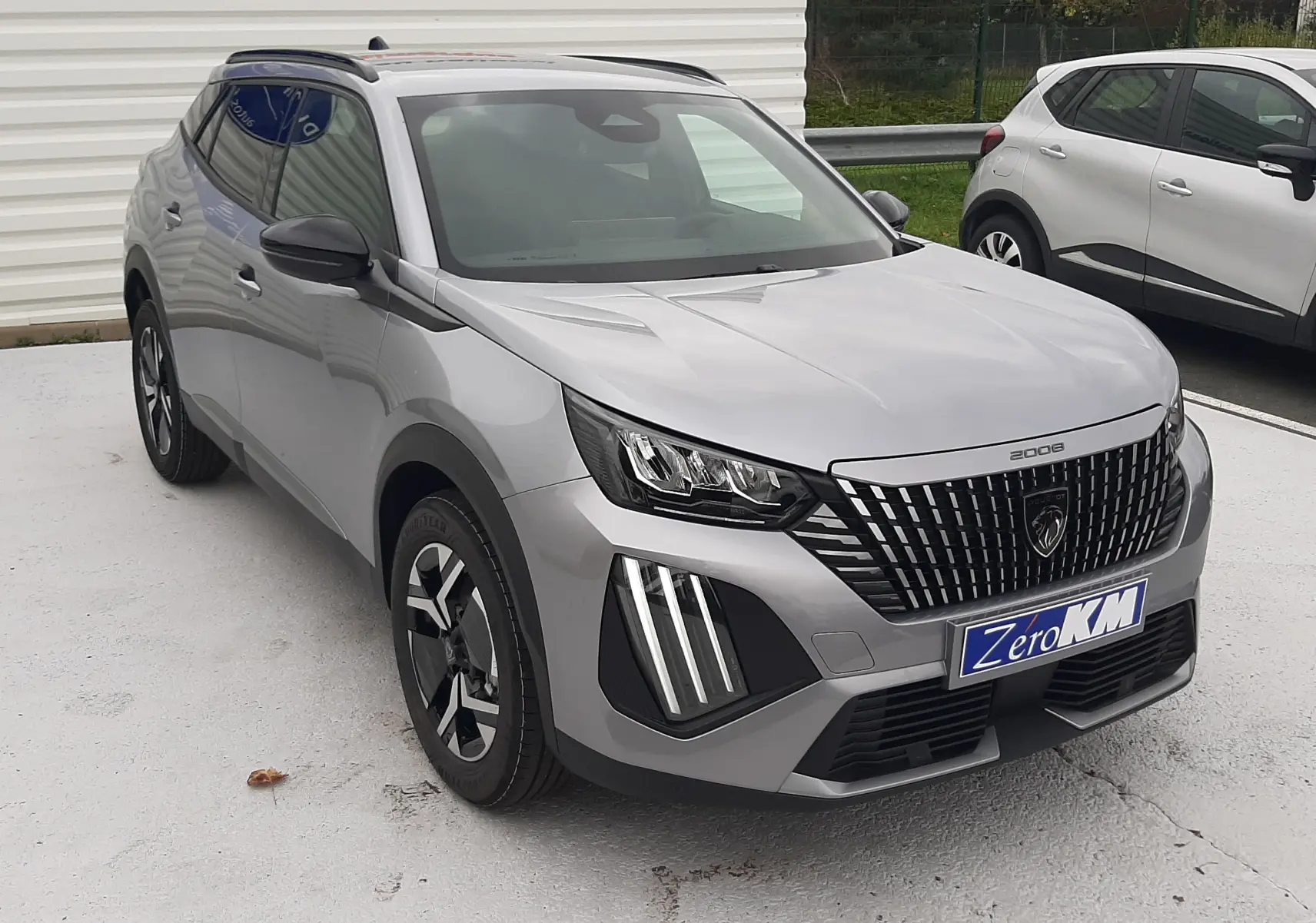 Peugeot 2008 gris Artense en 3/4 avant droit, avec calandre verticale distinctive et feux LED en griffes.