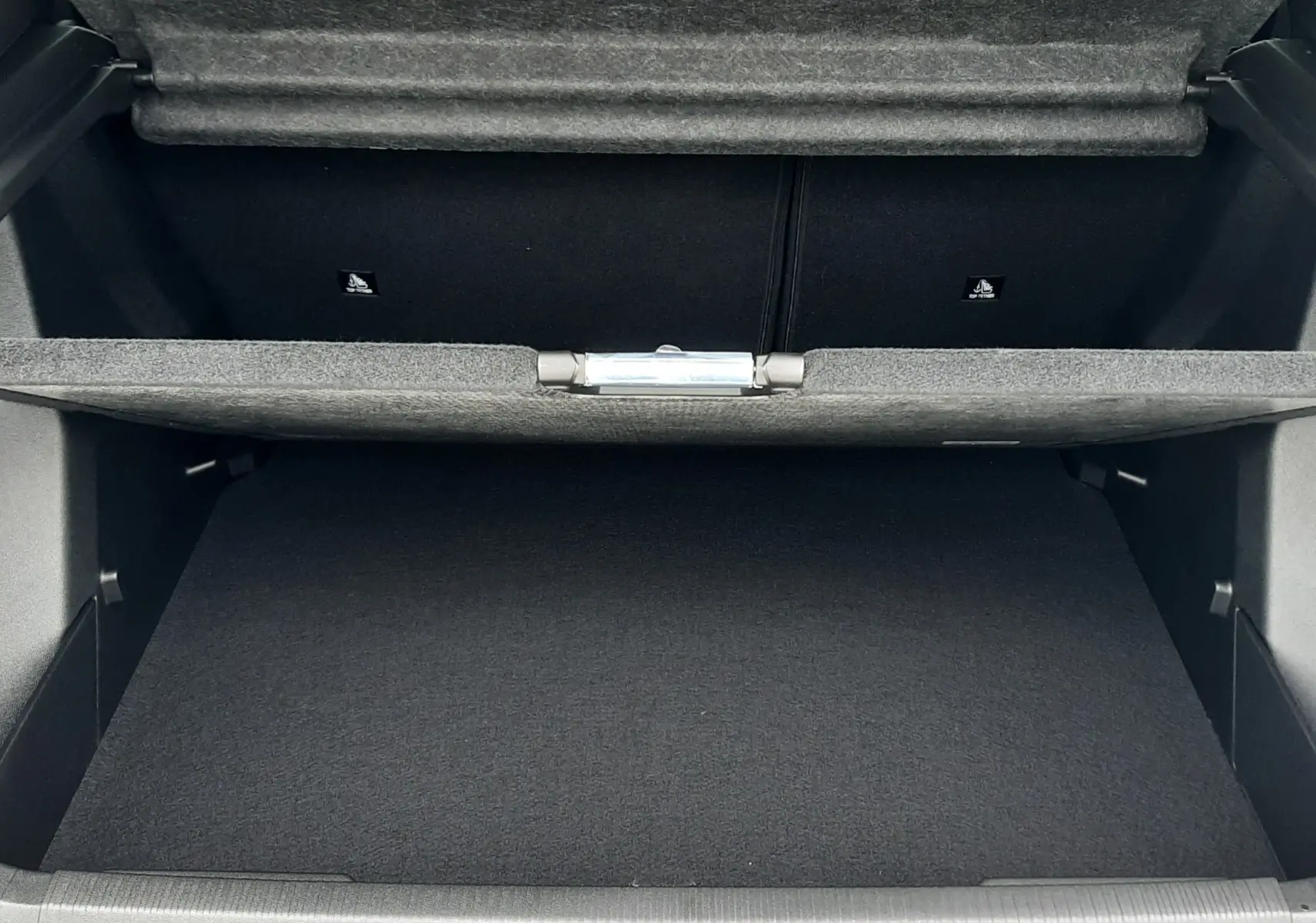 Coffre ouvert du Peugeot 2008 gris Artense, vue de l'arrière montrant l'espace de rangement et la doublure intérieure noire.